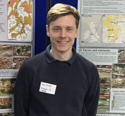 A student smiling in front of a poster